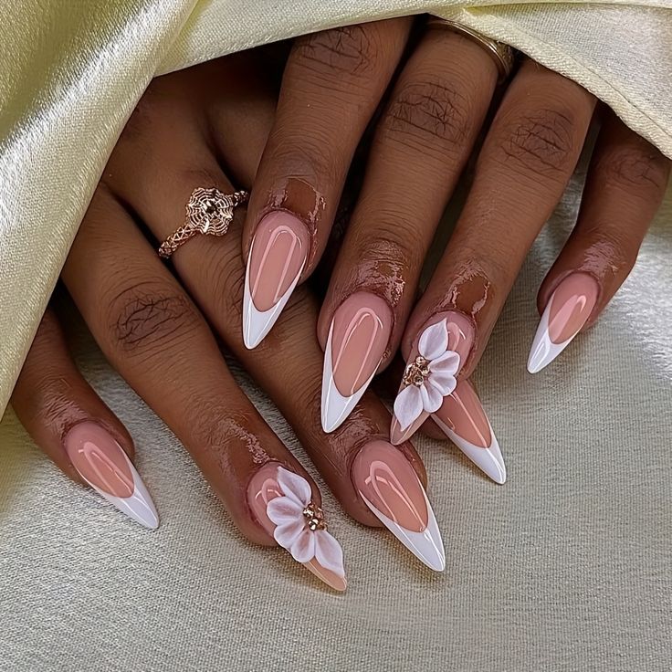 Blush and white French-tip nails decorated with raised white flowers and gold accents